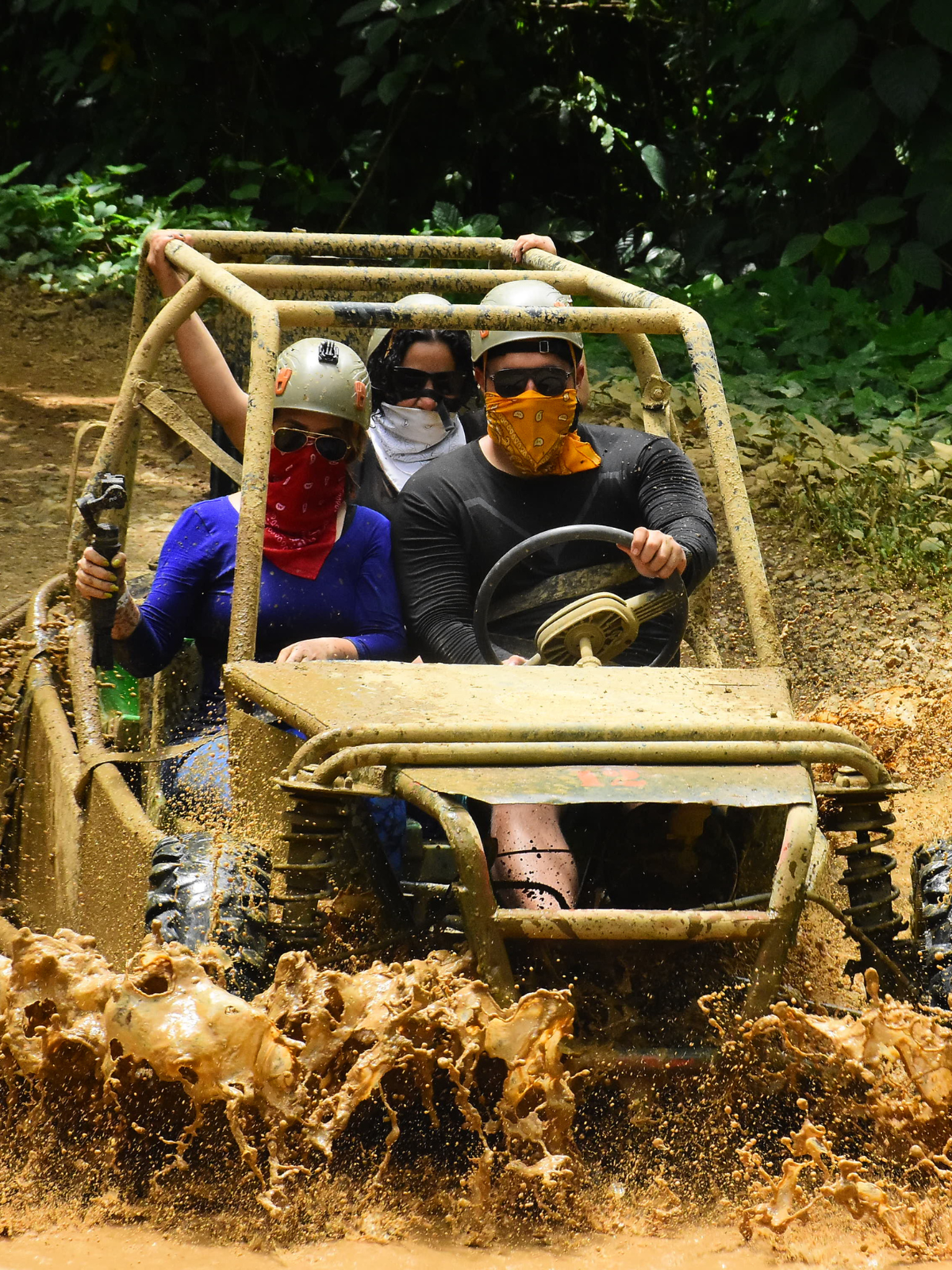 Grupo de personas conduciendo buggies todo terreno a través de una ruta con barro.