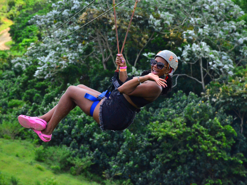 Girl ziplining over the canopy of a tropical forest at La Hacienda Park, Punta Cana.